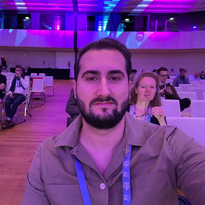 Ersan at an event in a hall lit in purple and blue.